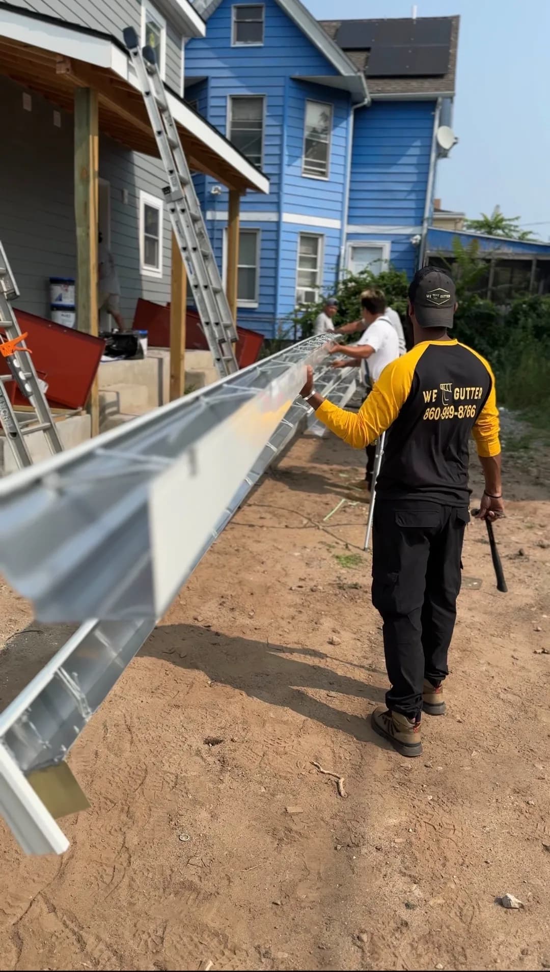 We Gutter crew carrying seamless aluminum gutter for installation on a Connecticut home — gutter installation in New Haven CT