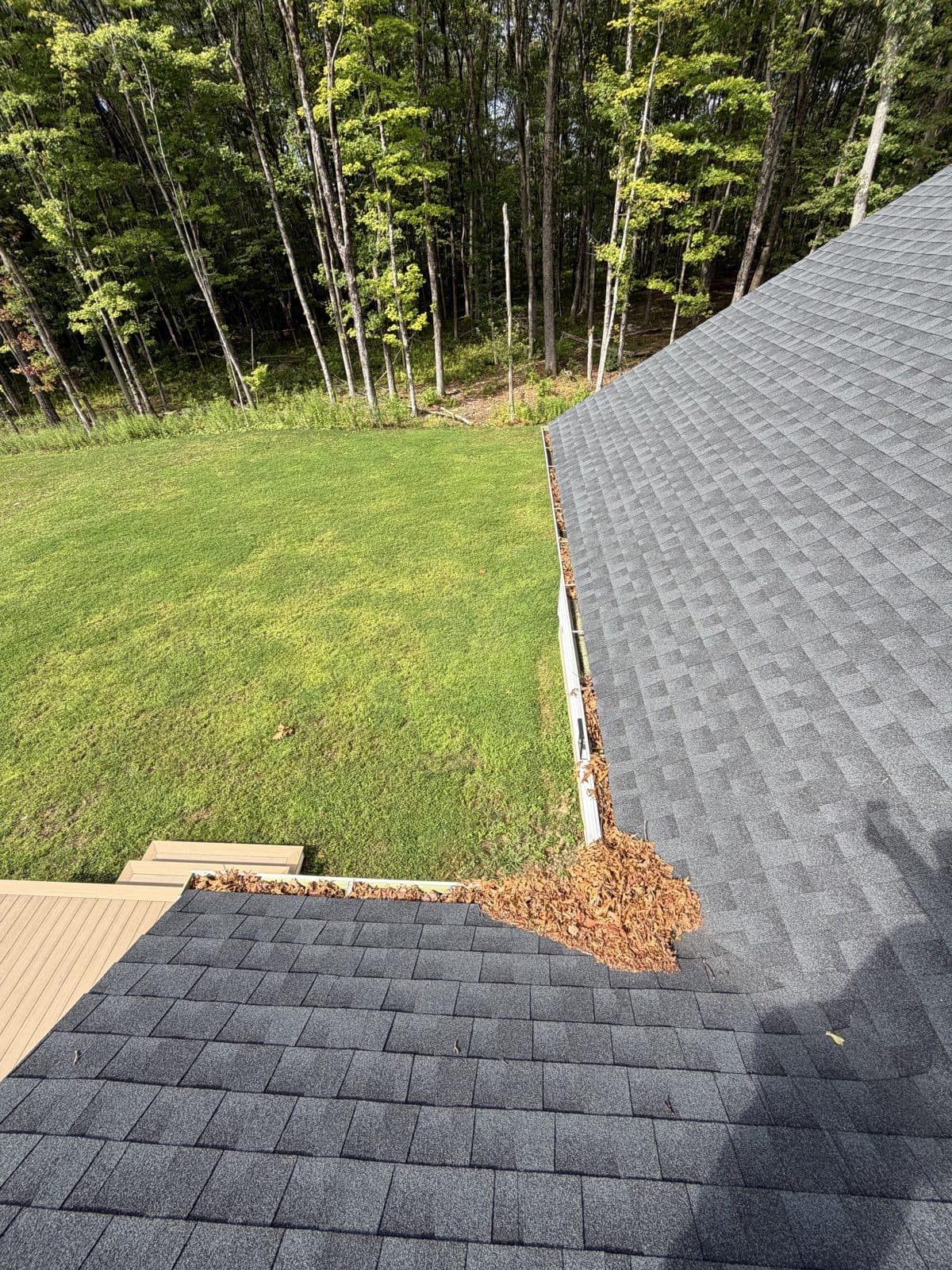 Roof-valley gutter corner in Harwinton, Connecticut, with accumulated leaves before cleaning.