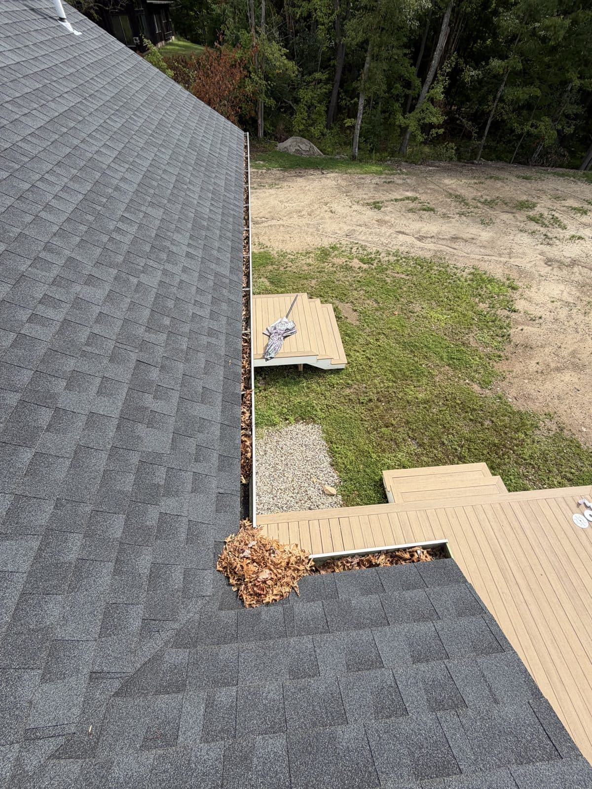 Deck-side gutter corner in Harwinton, Connecticut, with accumulated leaves before cleaning.